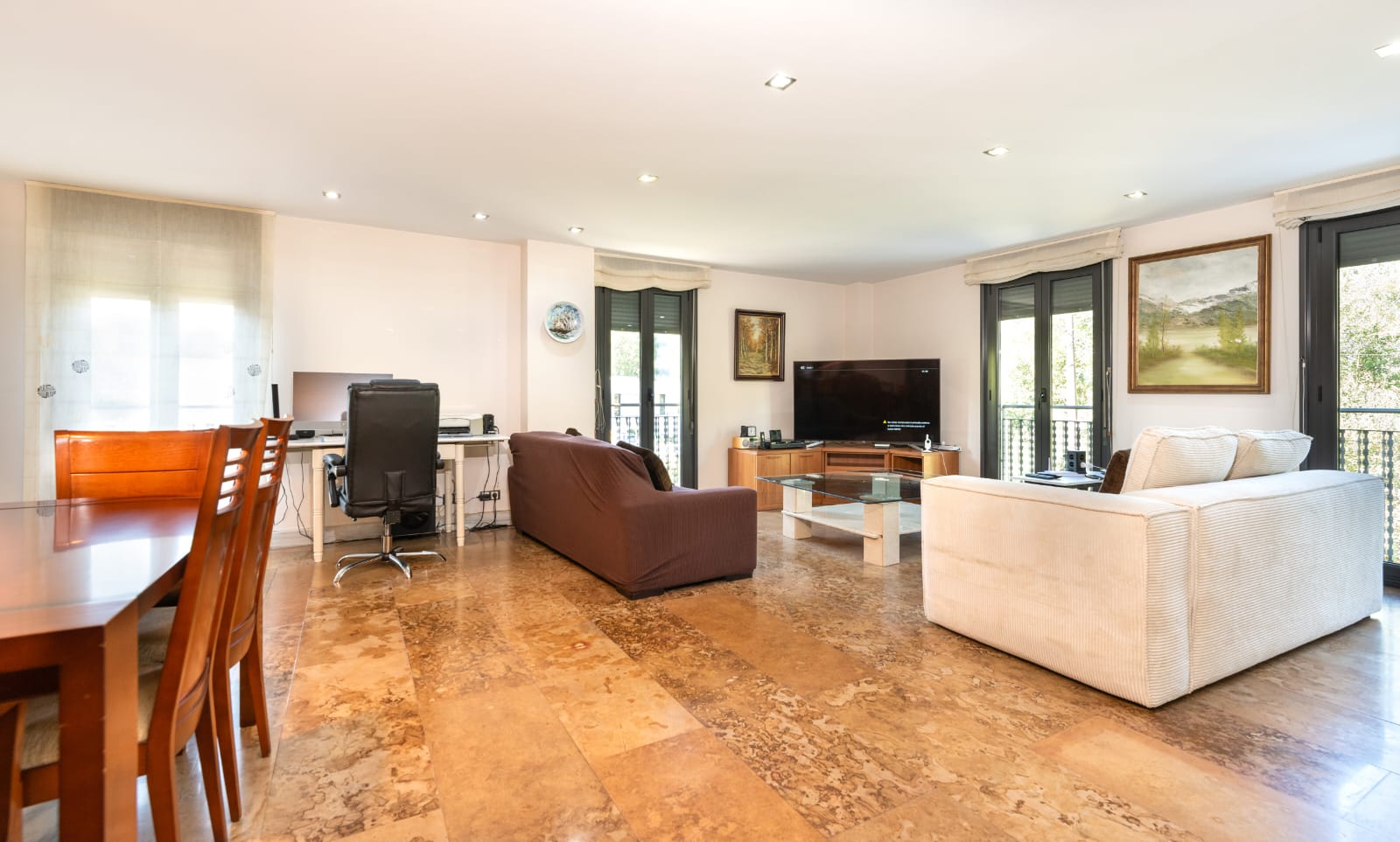 Salón principal con suelo de pizarra y balcones al jardín